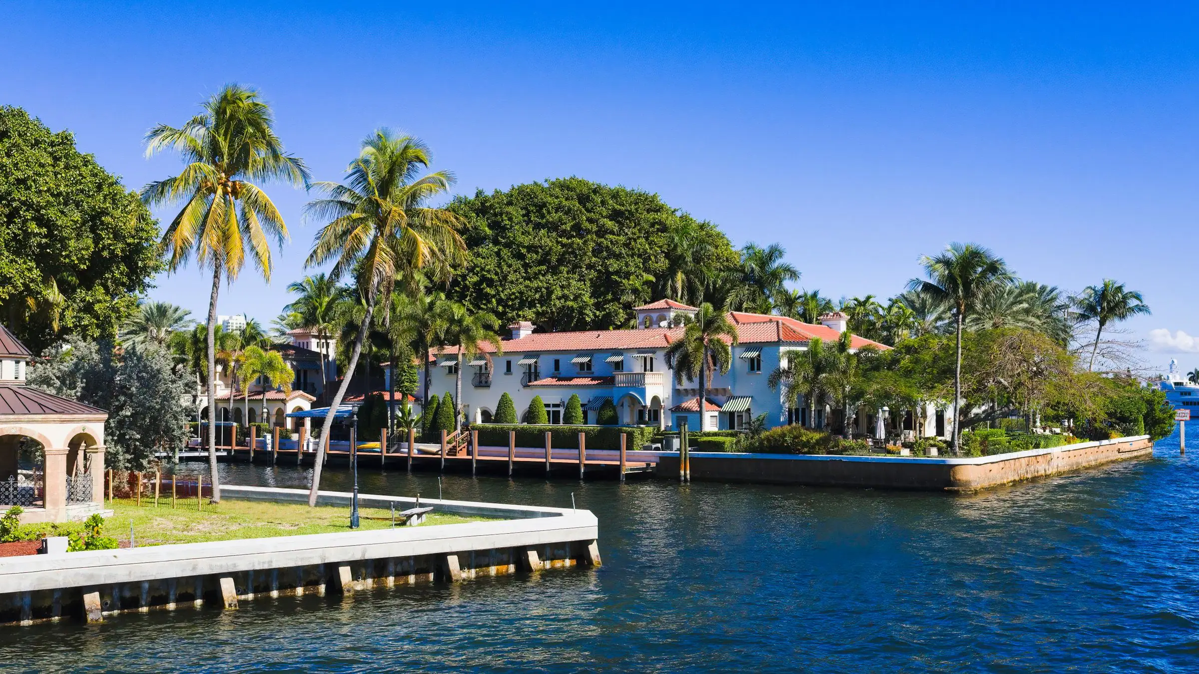 Canal front homes with palm trees and docks under a blue sky