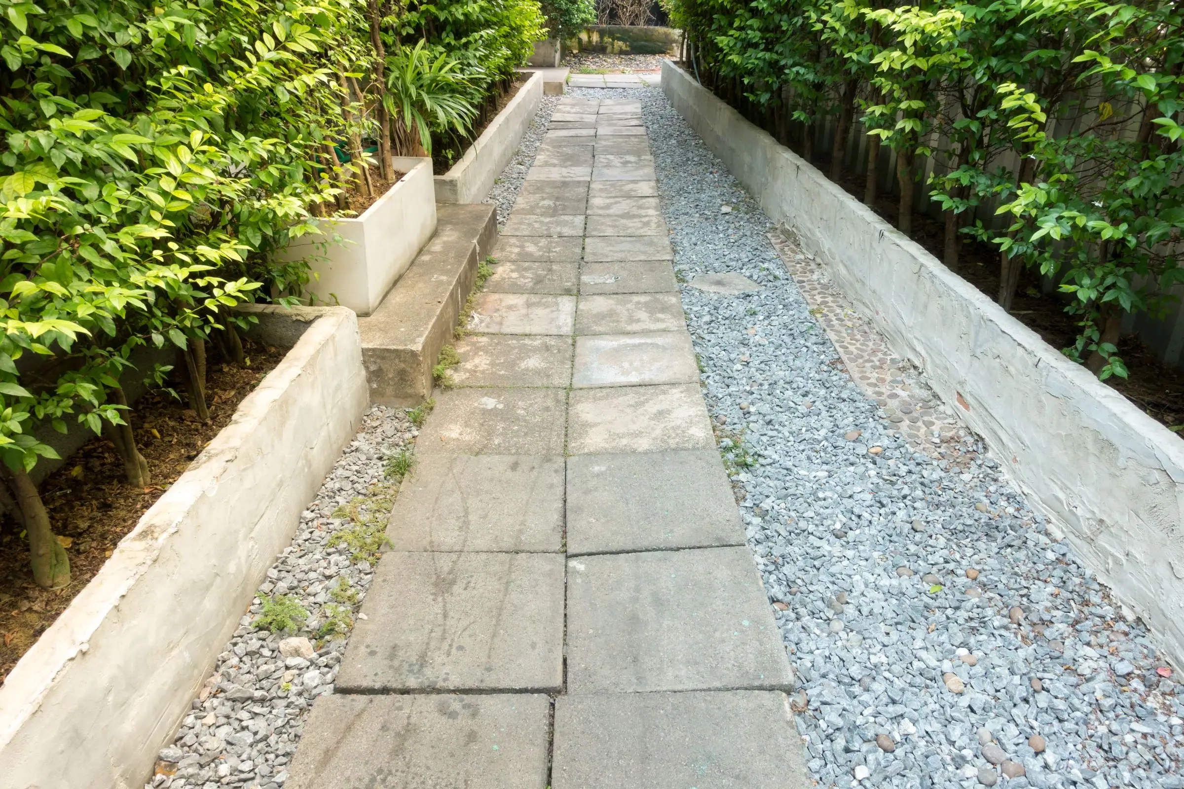 Paver walkway along the side of a house beside a gravel strip